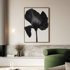 A modern living room features a green sofa, marble-topped console, and the Eclipse Bloom Canvas Art—a large black-and-white floral piece—hanging above, with a vase of dried flowers to complete the elegant decor.