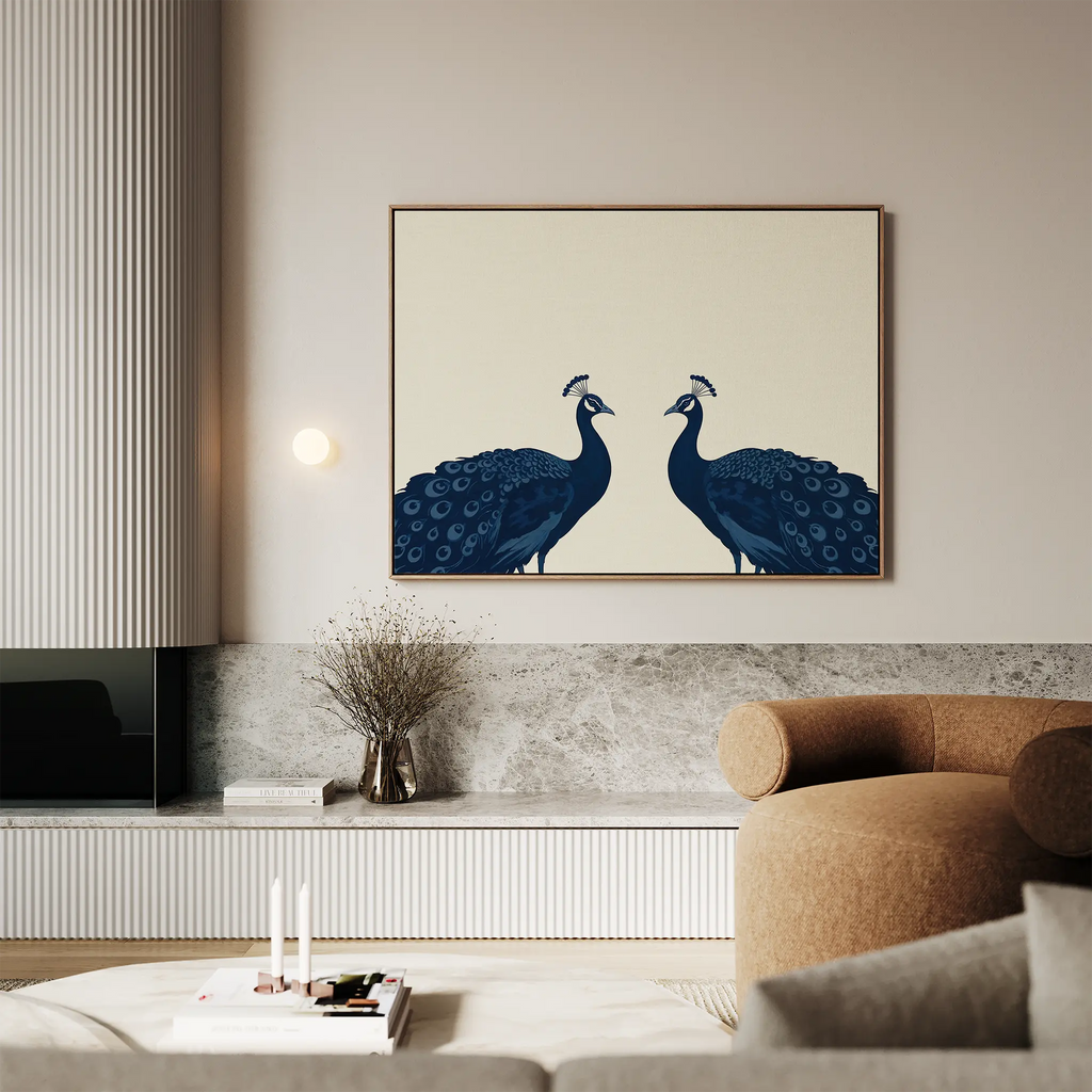 A modern living room with a curved beige sofa, marble accents, and the Elegant Plumage Canvas Art—striking wall decor featuring two blue peacocks facing each other on a light background to elevate your space.