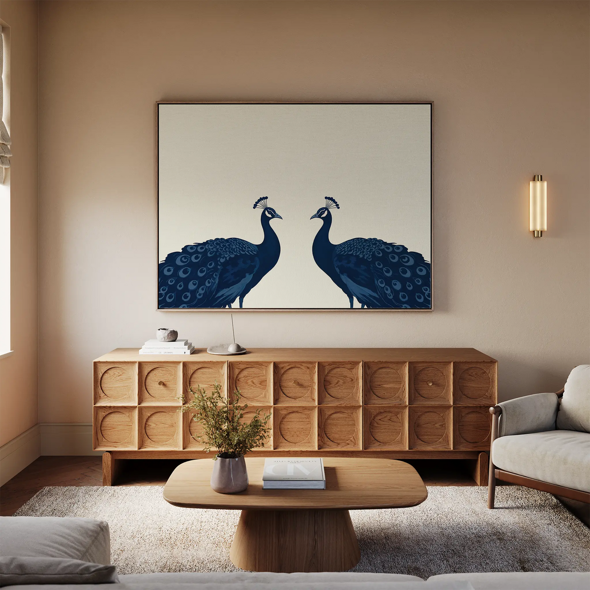 A modern living room featuring a wooden sideboard, a coffee table with a vase, and the Elegant Plumage Canvas Art of two blue peacocks facing each other on a beige wall—perfect for sophisticated decor.