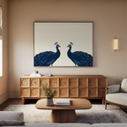 A modern living room featuring a wooden sideboard, a coffee table with a vase, and the Elegant Plumage Canvas Art of two blue peacocks facing each other on a beige wall—perfect for sophisticated decor.