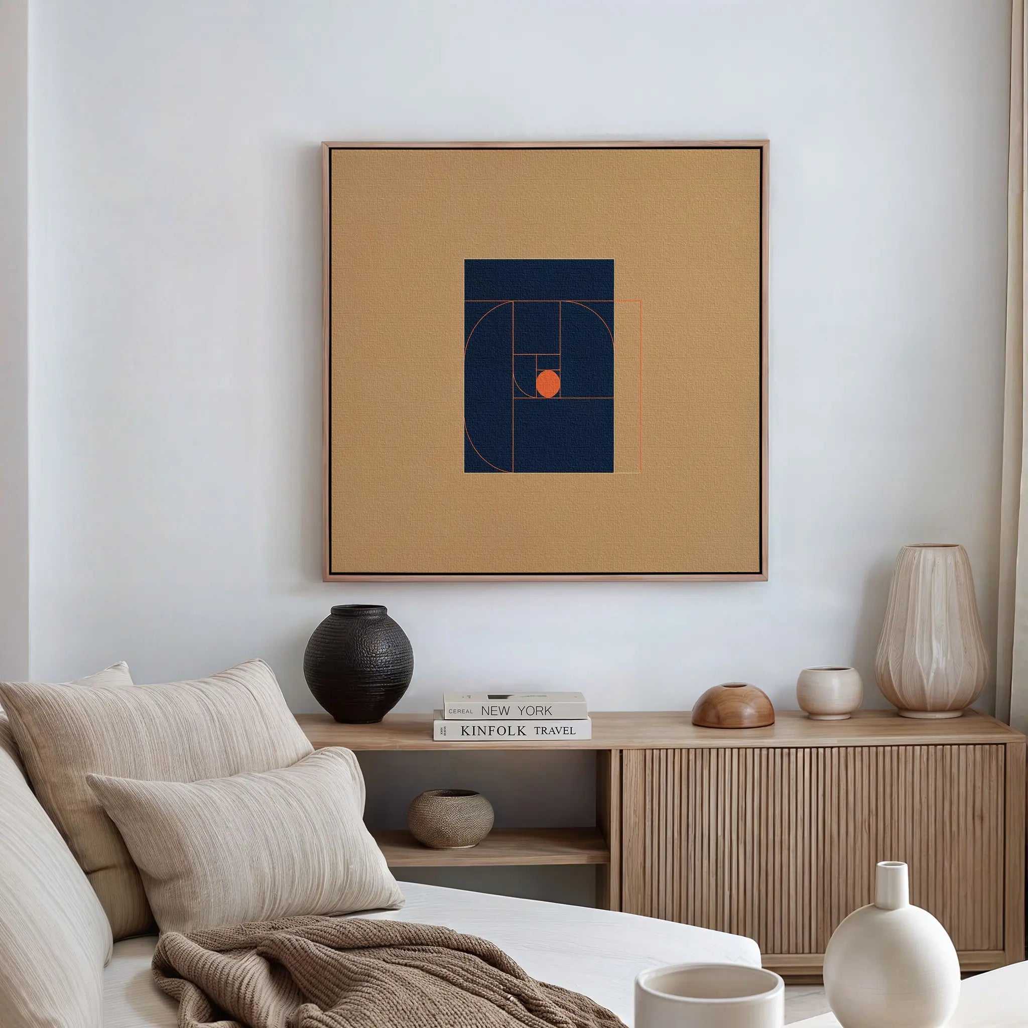 A modern living room features a beige sofa, neutral cushions, wooden sideboard, ceramic vases, stacked books, and the striking Ember Point Canvas Art with bold dark blue and orange shapes—perfectly capturing refined modern decor.