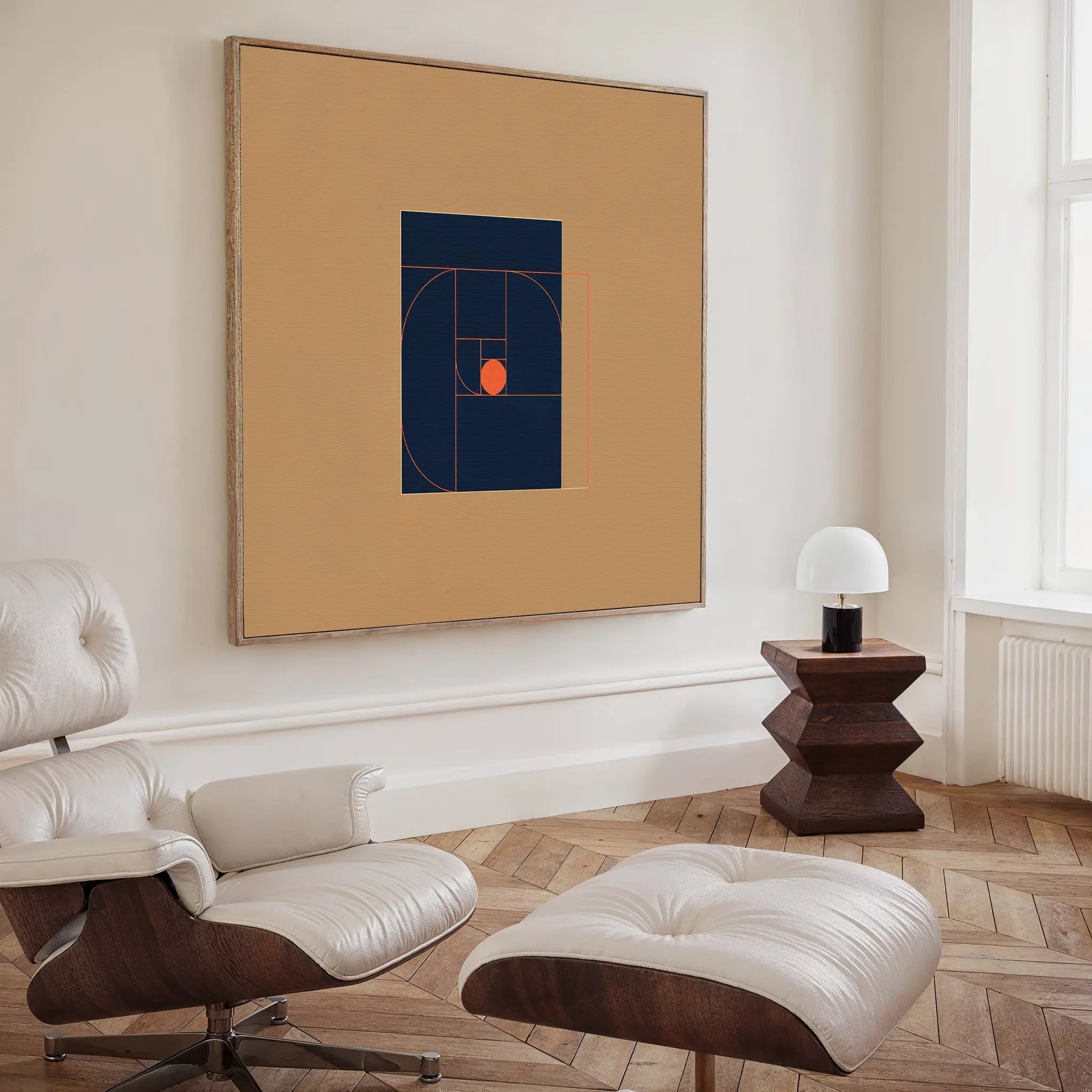 A modern living room features a white leather lounge chair and ottoman, a geometric wooden side table with a white lamp, and the Ember Point Canvas Art with striking abstract shapes and lines on a beige wall for contemporary decor.