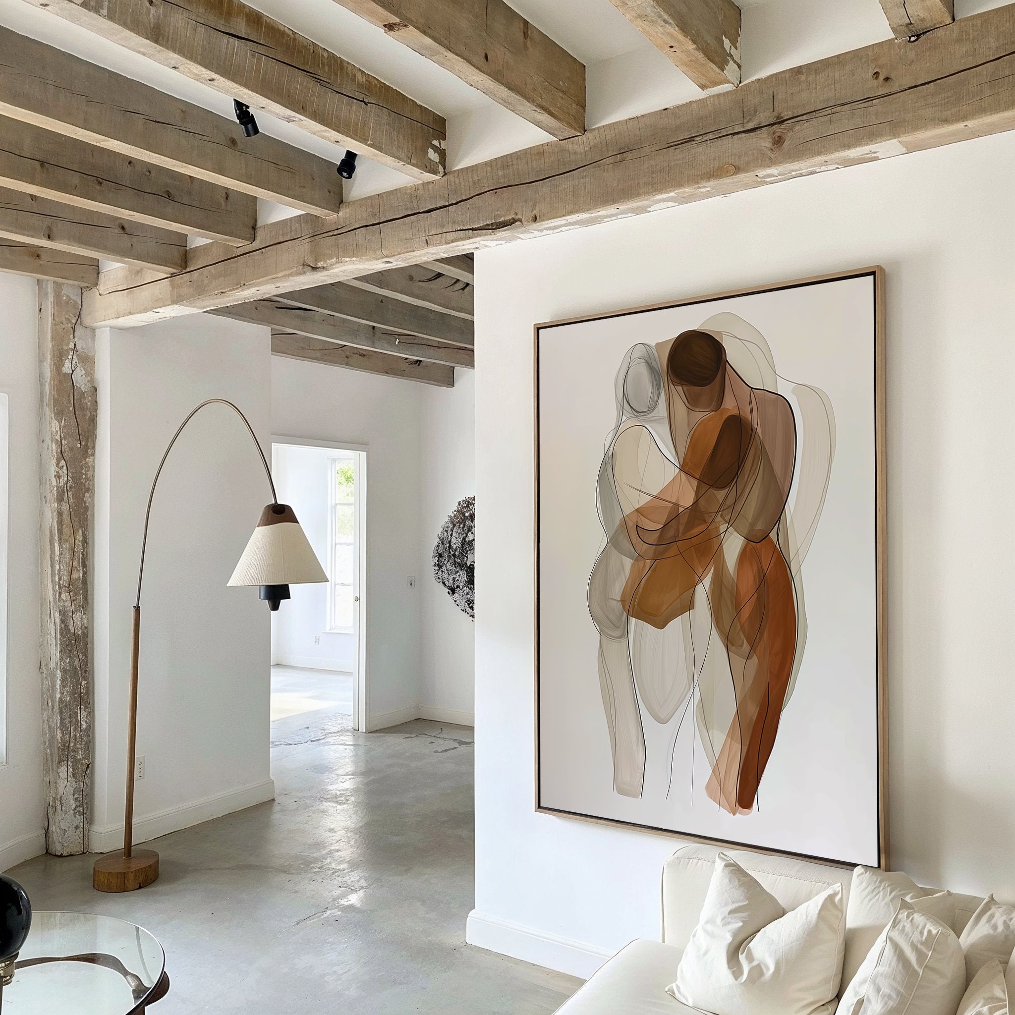 A modern living room with exposed wooden beams, a curved floor lamp, a white sofa, and the Embrace Abstract Canvas Art featuring two embracing figures in earthy tones adds a stylish touch to the decor.