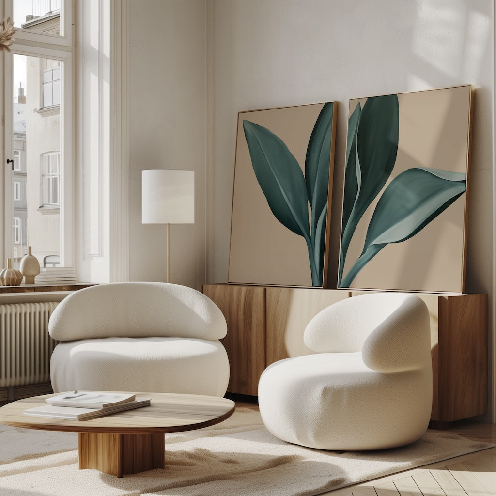 A modern living room features the Emerald Poise Set of 2 rounded white chairs, a wooden coffee table, a floor lamp, and green leaves wall art on a sideboard—perfect for enhancing bright, sunlit decor with stylish comfort.