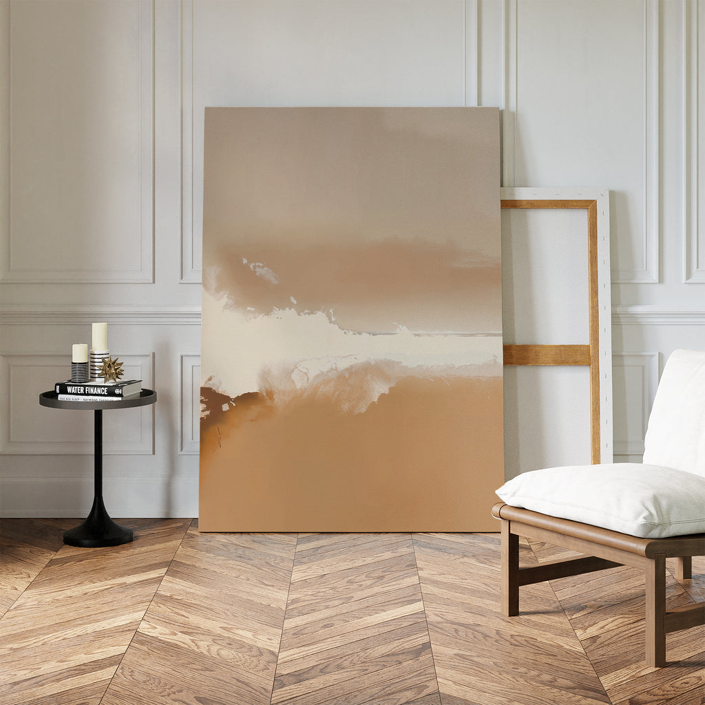 A minimalist room with herringbone wood floors features the Ethereal Plains Abstract Canvas Art in beige and brown tones, leaning against the wall beside an empty frame, a white cushioned chair, and a small black table with books and candles.