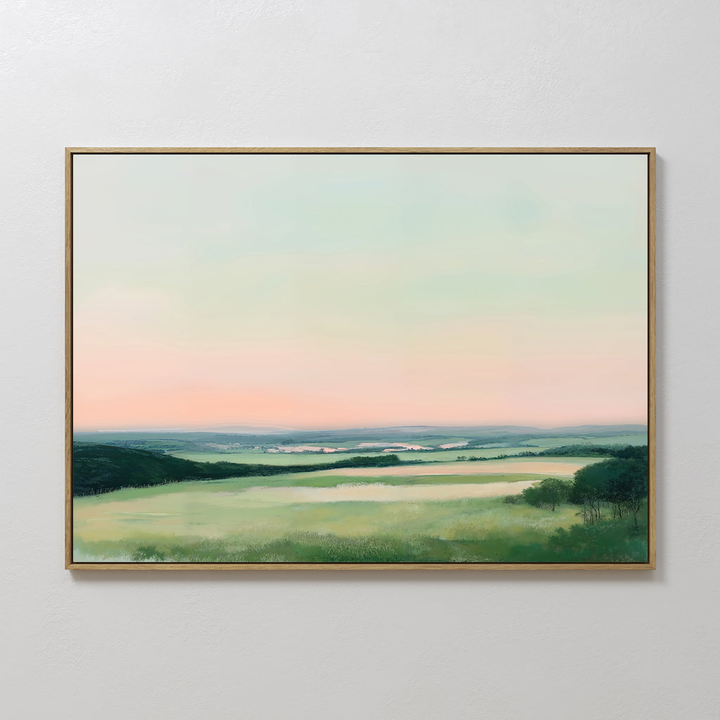 The "Evening Hues Canvas Art – Horizontal" displays a green, grassy field with distant hills beneath a pastel sky at dawn or dusk—ideal living room decor for display on a white wall.