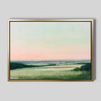The "Evening Hues Canvas Art – Horizontal" showcases green fields, distant hills, and a pastel sky at dusk—ideal framed wall decor for living rooms with light gray walls.