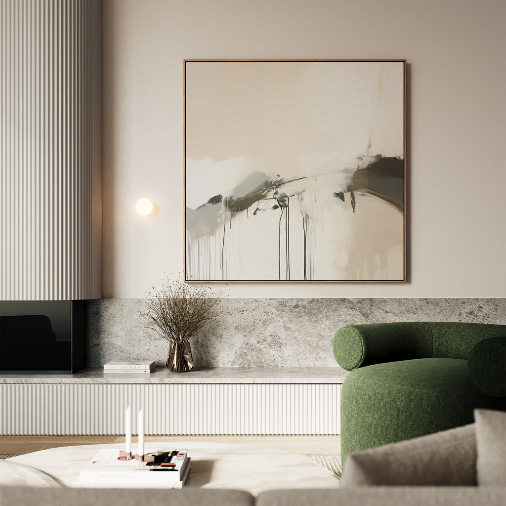 A modern living room with a green armchair, a round coffee table holding books and candles, a low marble shelf, a vase of dried branches, and the Faded Memory Canvas Art on a light-colored wall.