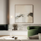 A modern living room with a green armchair, a round coffee table holding books and candles, a low marble shelf, a vase of dried branches, and the Faded Memory Canvas Art on a light-colored wall.