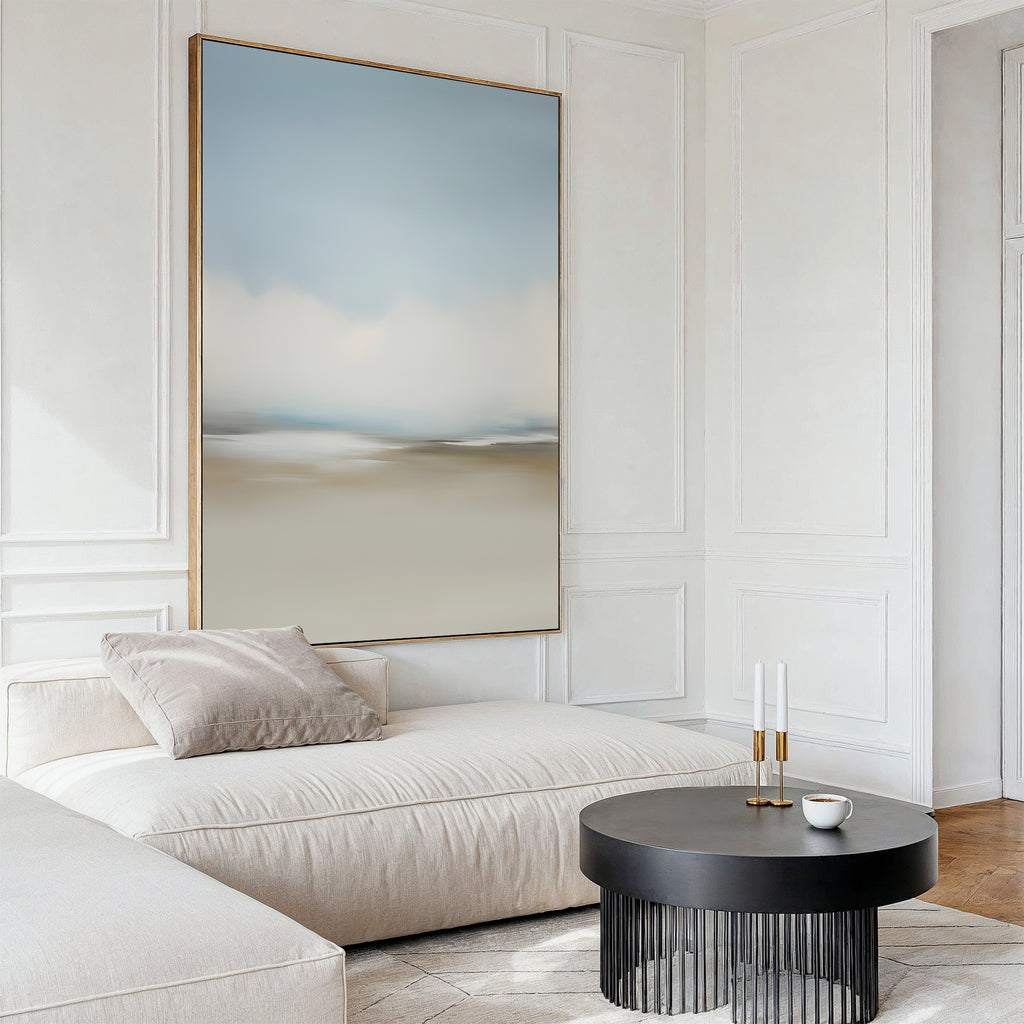 A modern living room features a cream sofa, a gray round coffee table with two candlesticks and a cup, and the Faded Silence Canvas Art in soft blue and beige tones as minimalist wall decor above the seating area.