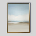 The Faded Silence Canvas Art is a framed abstract piece with soft, blurred blue, white, and beige tones in a minimalist design. This wall art features a gold frame and is displayed against a light gray wall.