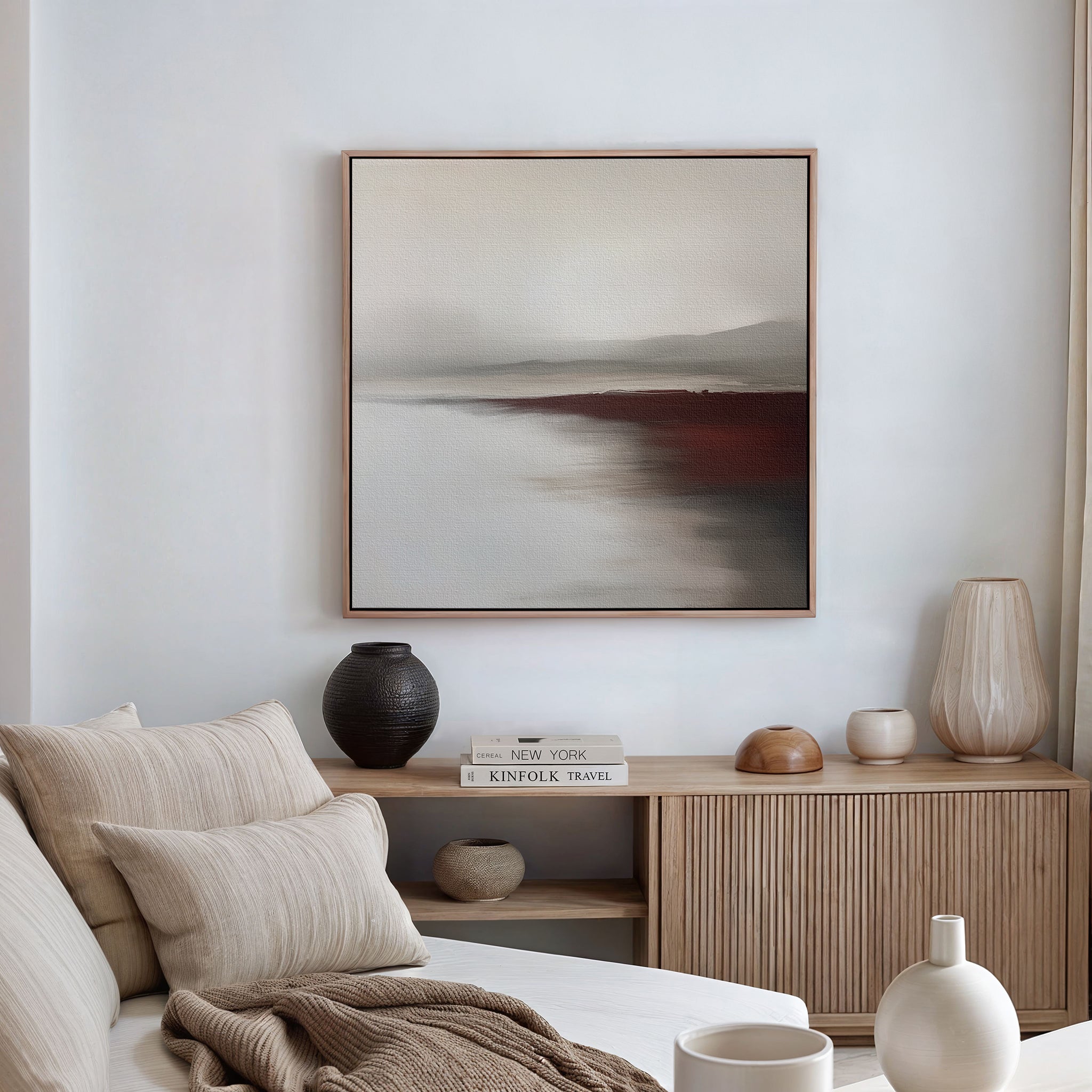 A minimalist living room featuring a beige sofa, neutral pillows, a wooden sideboard with vases and books, and the Fading Light Canvas Art in soft earth tones that elevates the decor.