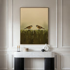 A modern console table with decorative objects stands against a white paneled wall. Above it hangs Fence Companions Canvas Art, depicting two birds on a weathered fence under a neutral sky—ideal for rustic bedroom decor.