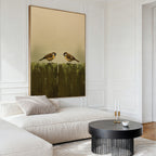 A modern living room featuring a white sectional sofa, a round black coffee table, and the Fence Companions Canvas Art of two birds on a green fence hanging above the sofa.