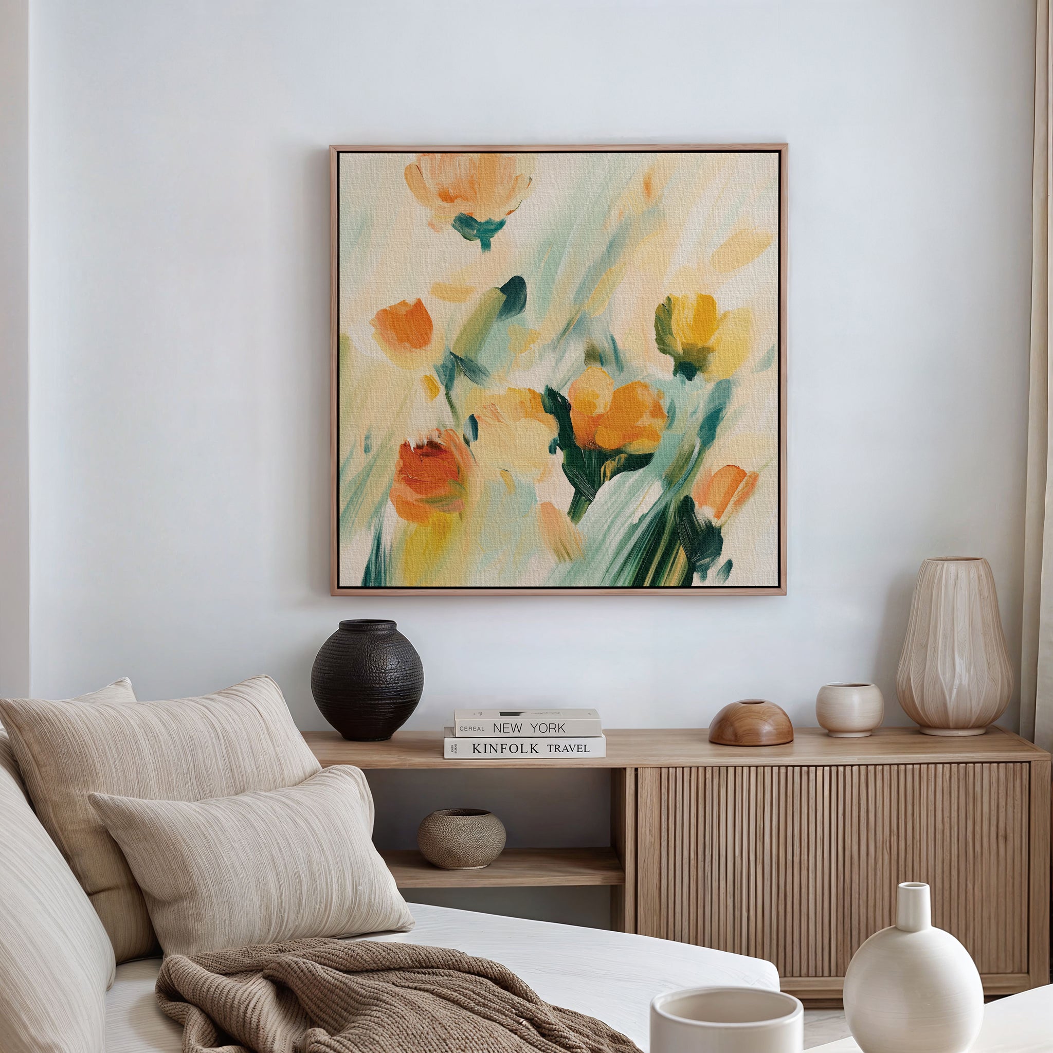 A cozy living room features a beige sofa, neutral cushions, and a wooden sideboard. Above, the Field Of Gold Canvas Art adds vibrance, while decorative vases and books on the sideboard bring a modern touch to the decor.