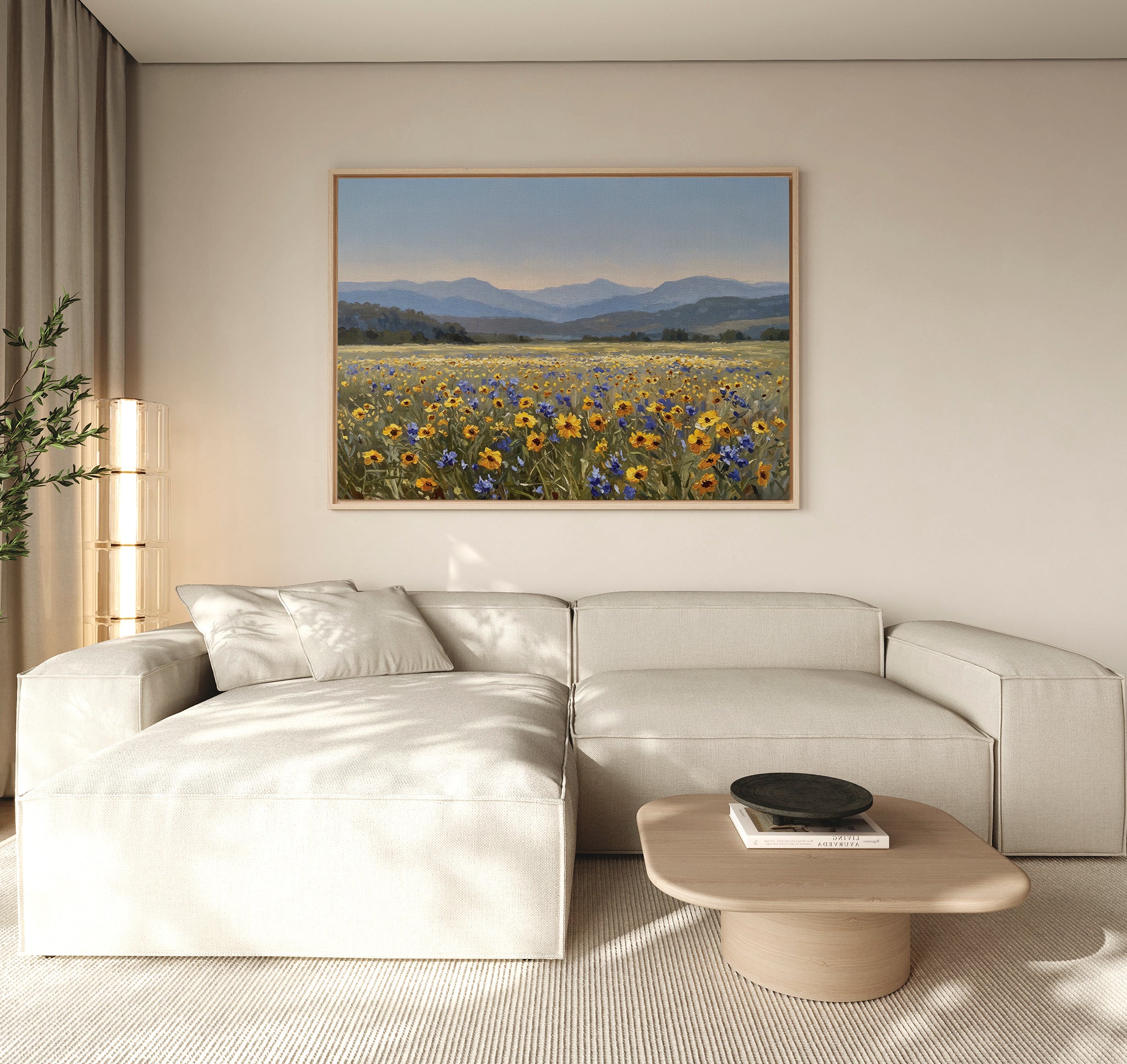 A modern living room with a light beige sectional sofa, a wooden coffee table, and the Fields of Color Canvas Art depicting a wildflower field with mountains hanging on the neutral-colored wall.