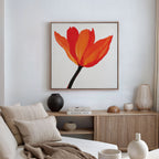 A minimalist living room featuring a beige sofa with pillows, wooden sideboard, ceramic vases, stacked books, and eye-catching Flame Tulip Canvas Art. Soft natural light from a window enhances the chic decor.