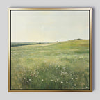 Floral Meadow Canvas Art features a sunlit green meadow with white wildflowers beneath a pale sky, extending to distant trees. Presented in a modern gold-colored frame, its ideal for brightening any living room decor.