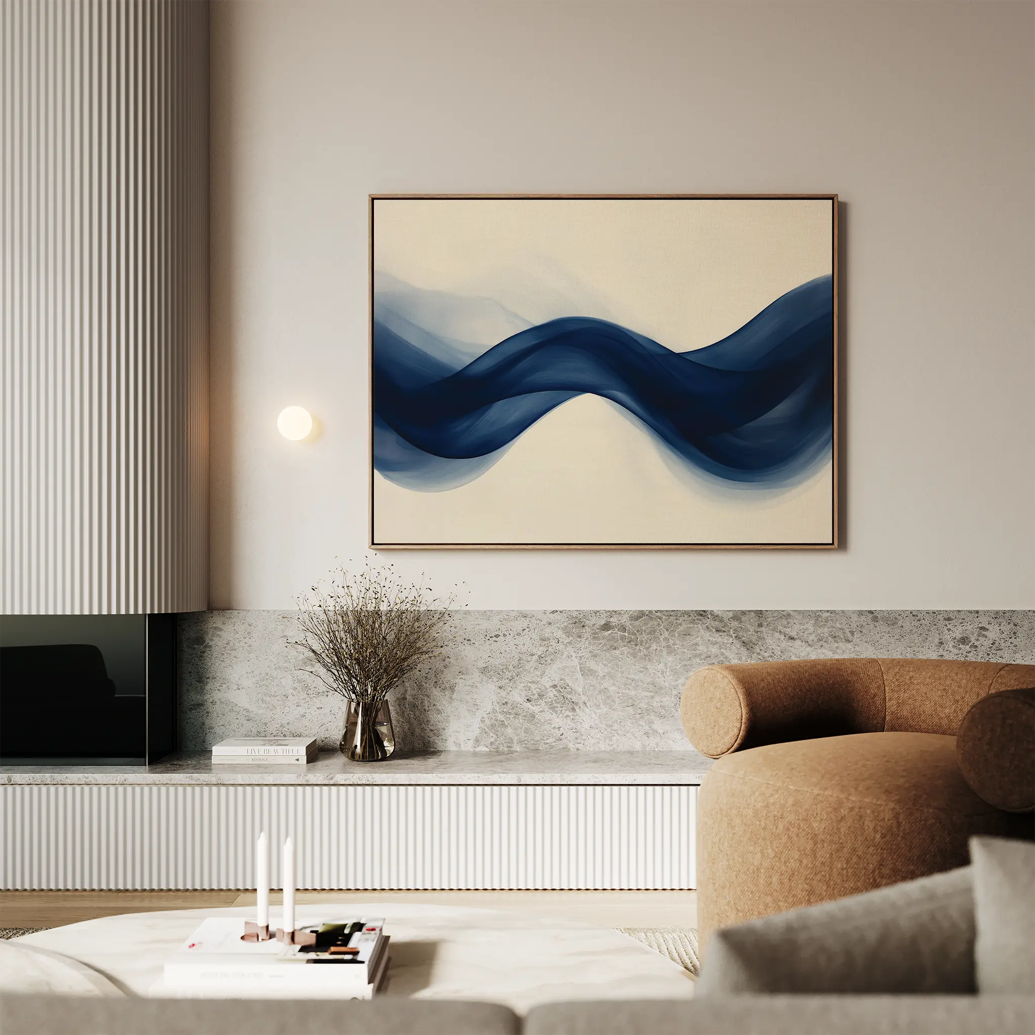 Modern living room with a beige armchair, marble surfaces, and minimalist interiors. The Flowing Indigo Canvas Art, featuring blue wave-like shapes, hangs above a small table with a vase of dried flowers.