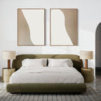A modern bedroom with an olive green upholstered bed, white bedding, two gold nightstands with beige lamps, and the Flowing Silhouettes Set of 2 wall art above the bed. A textured gray and white rug adds a refined touch to the floor.