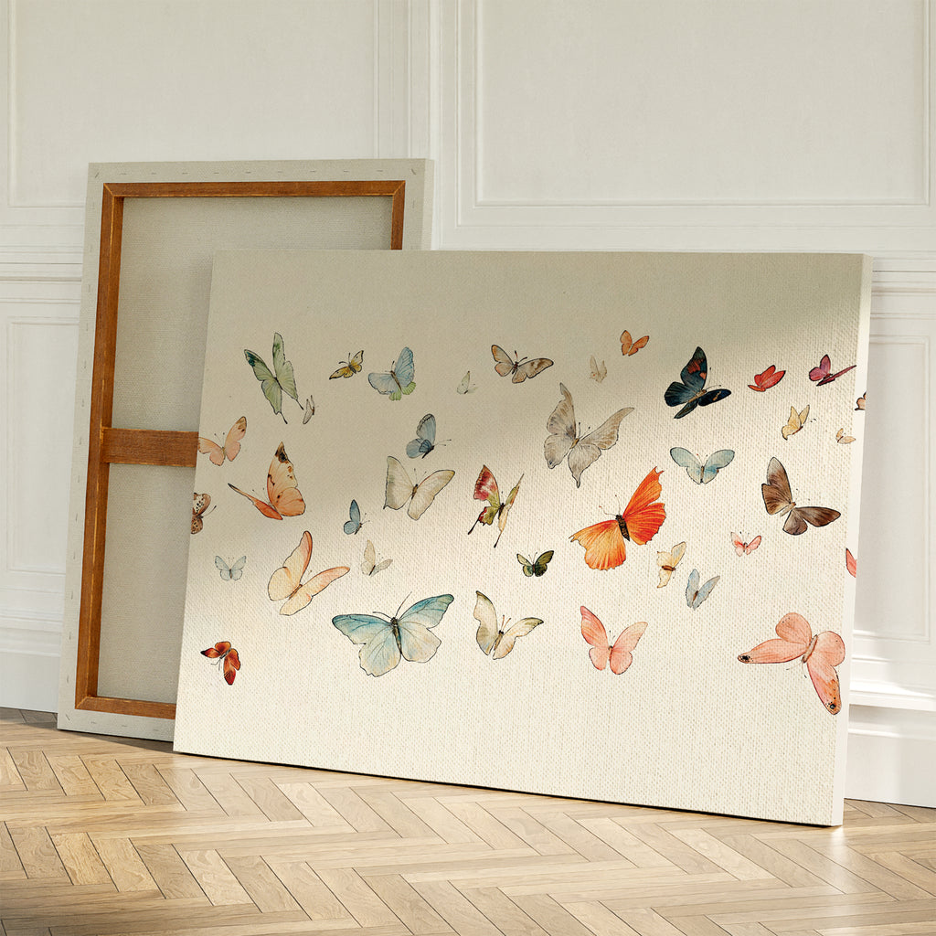 The Fluttering Dreams Abstract Canvas Art, featuring vibrant butterflies, is propped against a wall with a blank canvas behind it on a wooden herringbone floor in a bright, airy room.