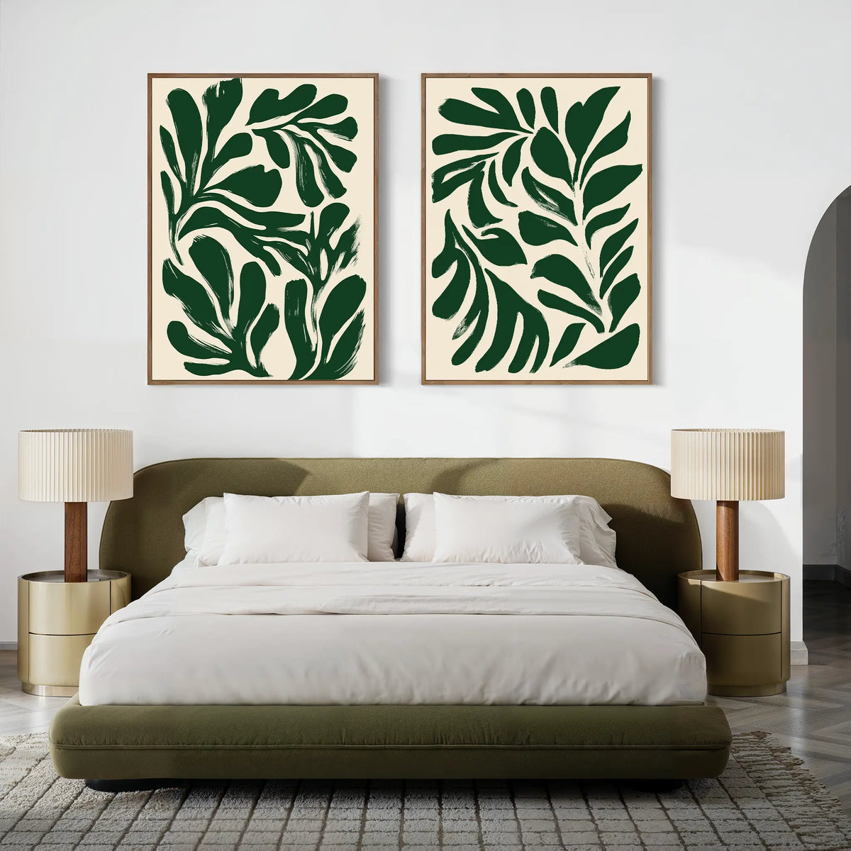 A modern bedroom with a green upholstered bed, white bedding, two bedside tables with matching lamps, and two large Forest Leaves Set of 2 botanical wall art prints displayed above the bed.