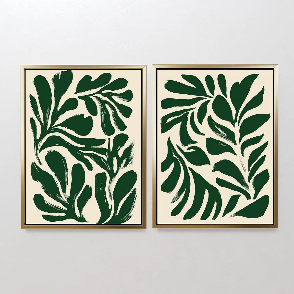 The Forest Leaves Set of 2 features framed prints with abstract green leaf shapes on a light background, displayed side by side. This botanical wall art adds bold, modern style and a minimalistic touch to any plain white wall.
