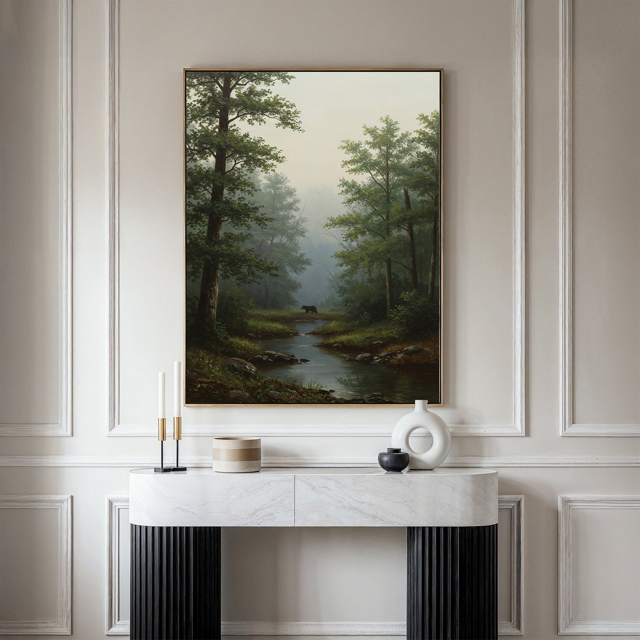 The Forest Passage Canvas Art, depicting a forest with a stream and distant black bear, is displayed on a cream wall above a modern marble console adorned with candles and neutral-toned vases.
