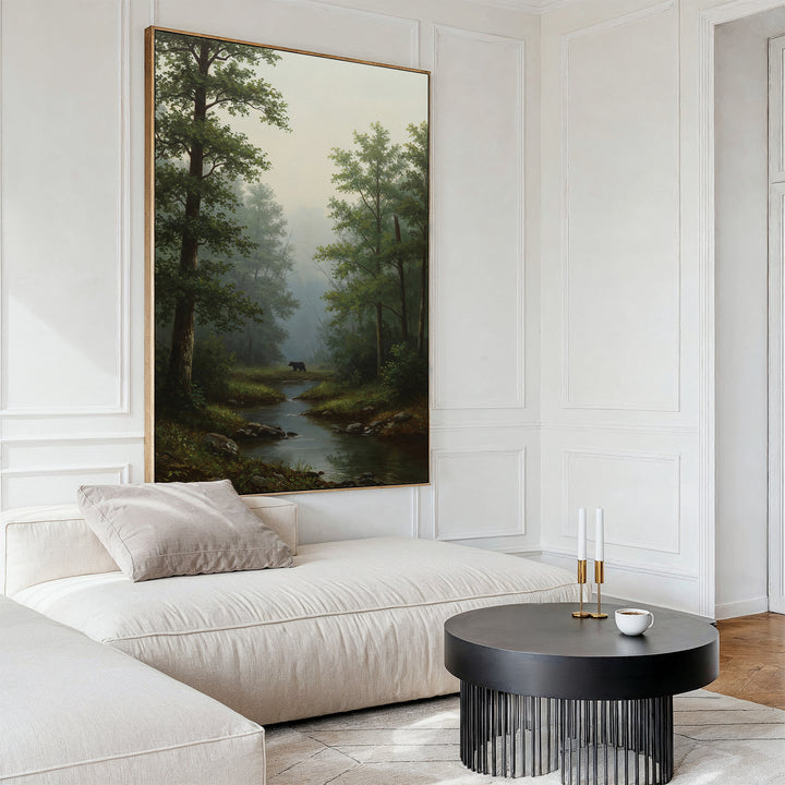 A modern living room with a cream sectional sofa, round black coffee table, and the Forest Passage Canvas Art—featuring trees, a stream, and a deer—hanging above the sofa.