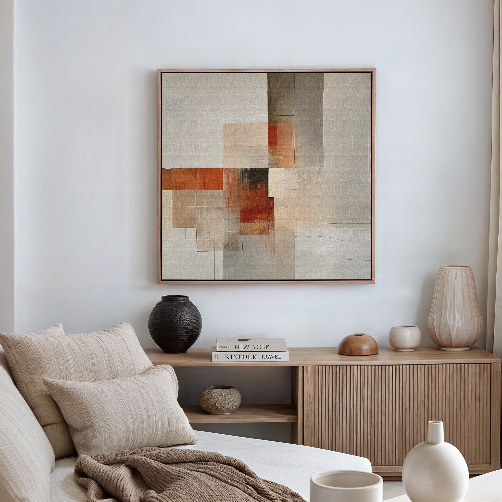 A modern living room with a beige sofa, neutral pillows, a wooden sideboard displaying vases and books, and the Fractured Light Canvas Art in earthy tones showcased above.