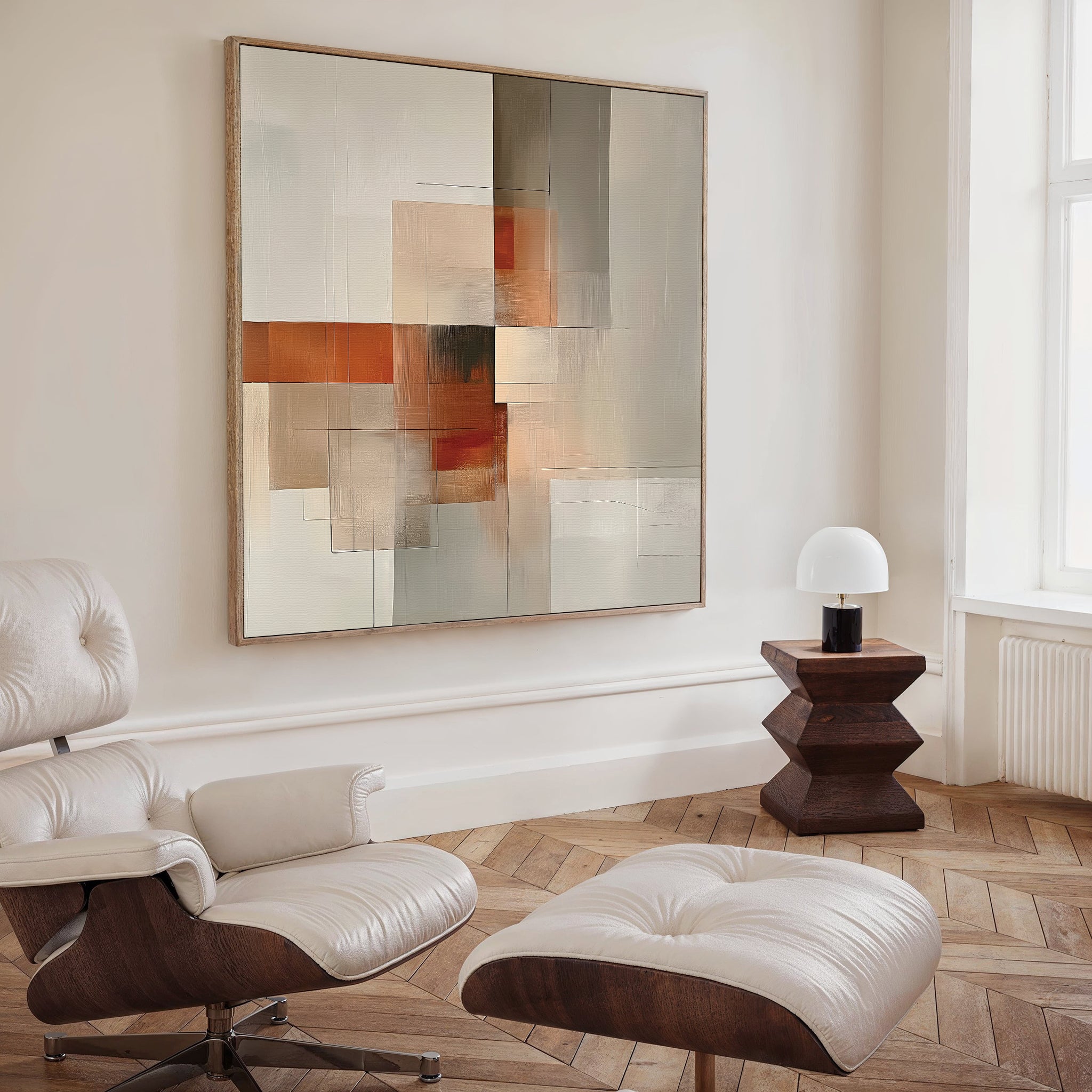 A modern living room features a white lounge chair with ottoman, a geometric wood side table with lamp, and the Fractured Light Canvas Art in neutral and orange tones, adding a sophisticated touch to the space.