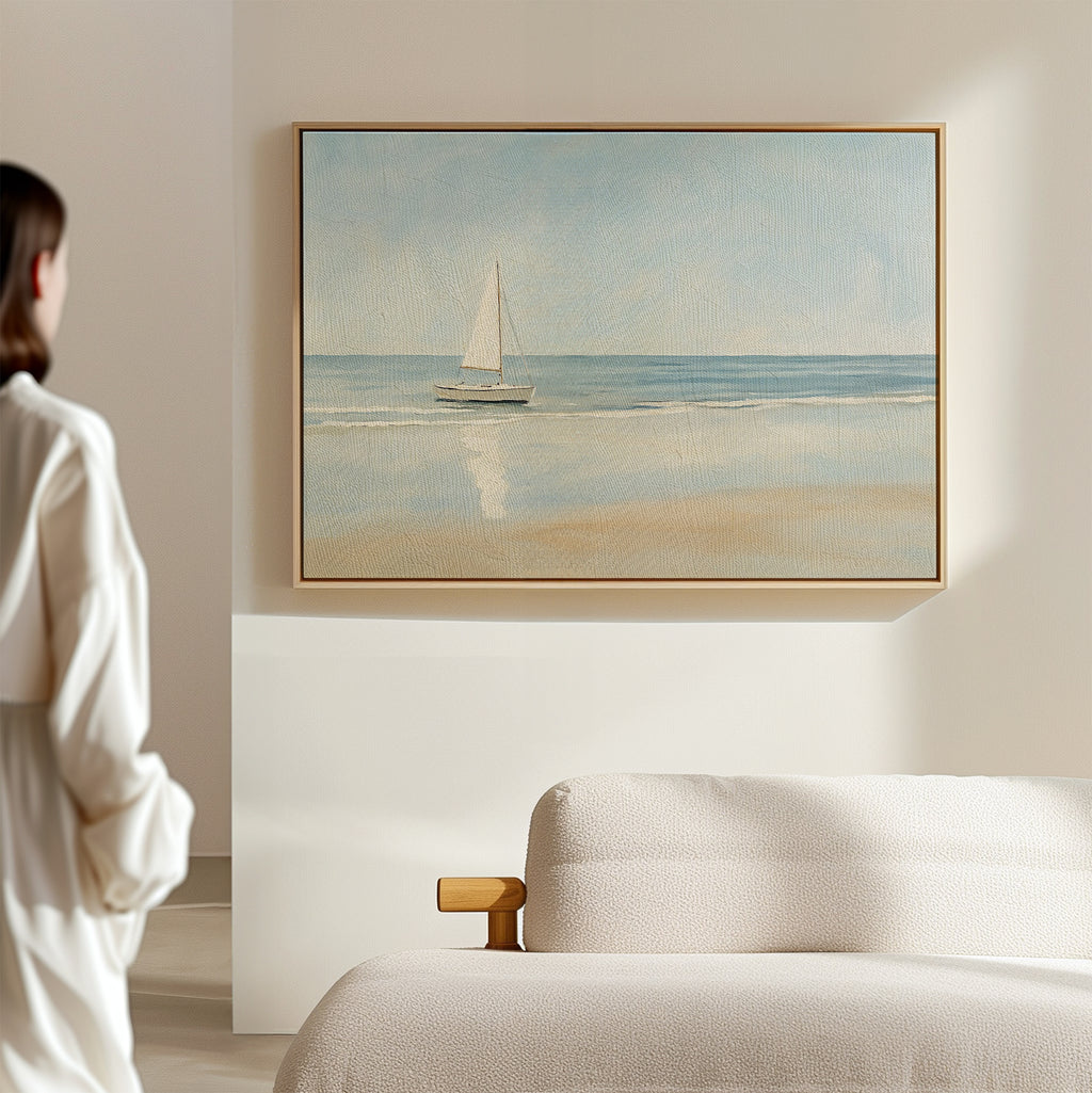 A woman in a white top stands in a sunlit, minimal room, admiring the Freedoms Call Canvas Art—a serene sailboat print above a light-colored sofa that brings tranquil decor to the space.