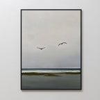 Freeflight Canvas Art is a framed painting of a calm seascape with two birds over gentle waves and a dark shore. Its minimalist, muted palette makes it perfect for adding tranquil decor to any space.