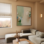 A modern living room with a beige sectional sofa, wooden coffee table with dried flowers, elegant decor accents, and a window with a Roman shade framing tree views. The wall features the Garden Bloom Canvas Art as a focal point.