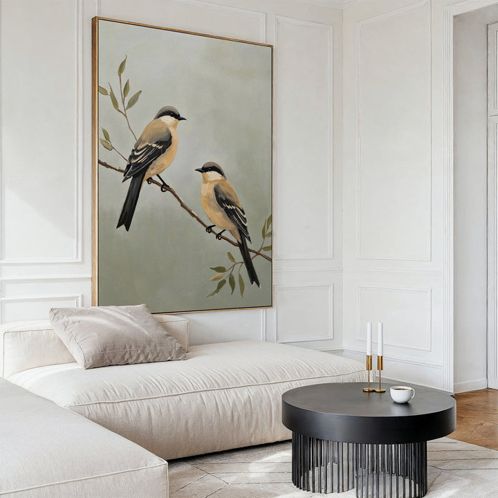 Minimalist living room featuring the Garden Pair Canvas Art of two birds on branches, a white sectional with neutral cushions, black coffee table, and candlesticks—perfect for a Nordic Park-inspired, airy space.