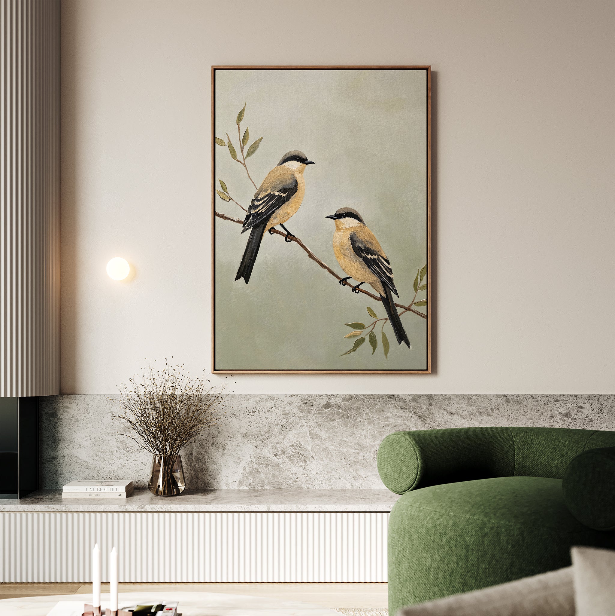 The Garden Pair Canvas Art, featuring two yellow and brown birds on a branch, hangs above a marble shelf, bringing Nordic Park charm to the living room alongside a green curved sofa and dried flowers in a vase.