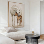 A modern living room with a white sofa, round black coffee table, and Gentle Bond Canvas Art featuring a white horse nuzzling a brown foal. Minimalist decor and neutral tones add calm sophistication.