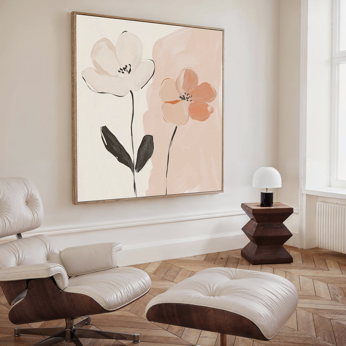 A modern living room features a cream lounge chair and ottoman, a dark wood side table with a white lamp, and the Gentle Duo Canvas Art—an abstract floral piece in soft pink and white tones that adds minimalist elegance.