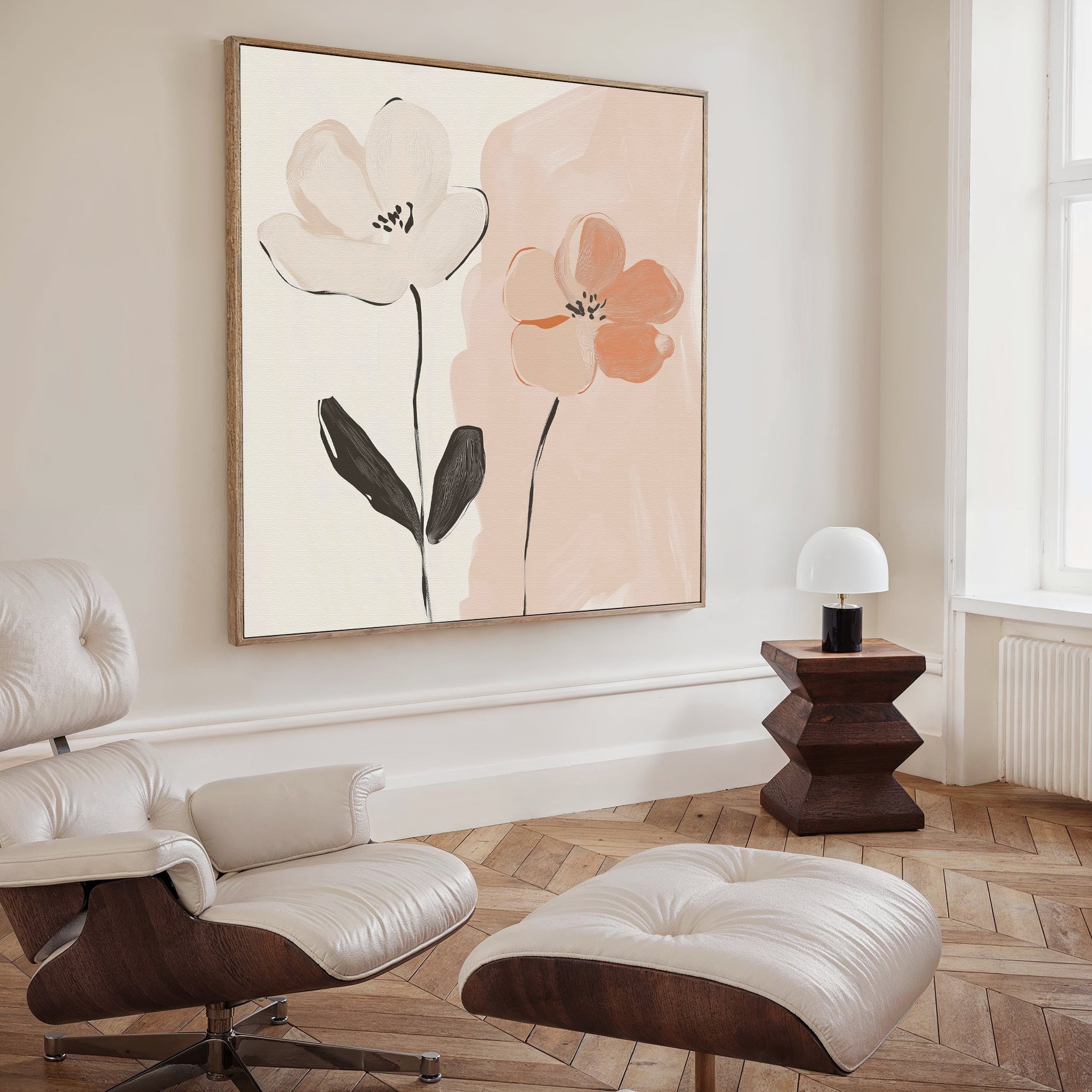 A modern living room features a cream lounge chair and ottoman, a dark wood side table with a white lamp, and the Gentle Duo Canvas Art—an abstract floral piece in soft pink and white tones that adds minimalist elegance.