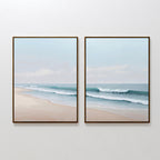 The Gentle Surf Set of 2 features two framed paintings—one depicting a sandy beach, the other gentle ocean waves under a light blue sky—creating calming coastal wall art perfect for living room decor.