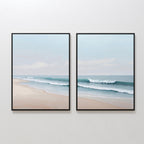 The Gentle Surf Set of 2 features framed paintings with soft waves meeting a sandy shore under a light blue sky, creating a serene coastal seascape ideal for bedroom or living room decor.
