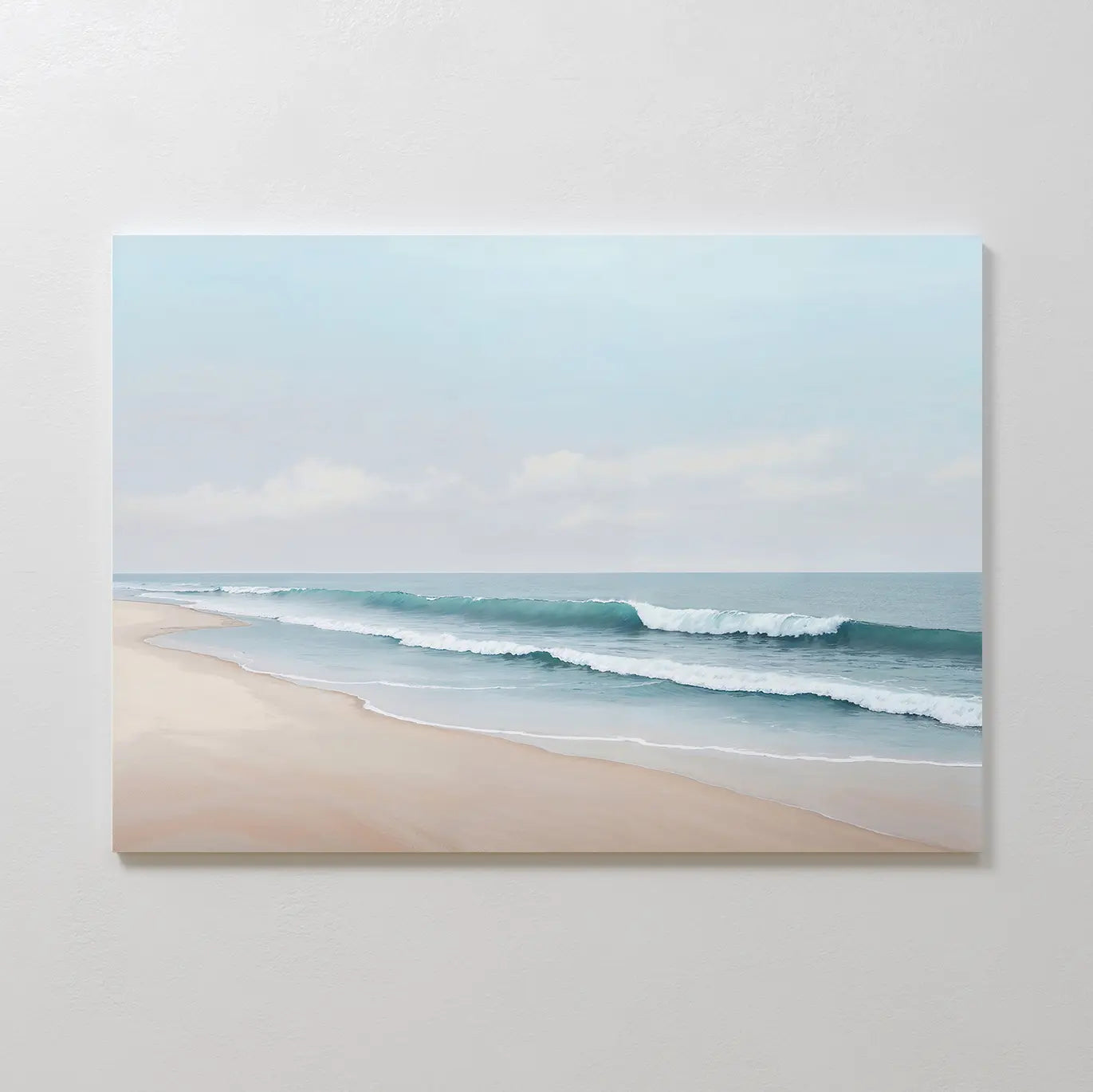 Gentle Surf Canvas Art depicts calm waves on a sandy beach beneath a cloudy sky, making it ideal coastal wall art for bedroom decor, beautifully displayed on a plain, light-colored wall.
