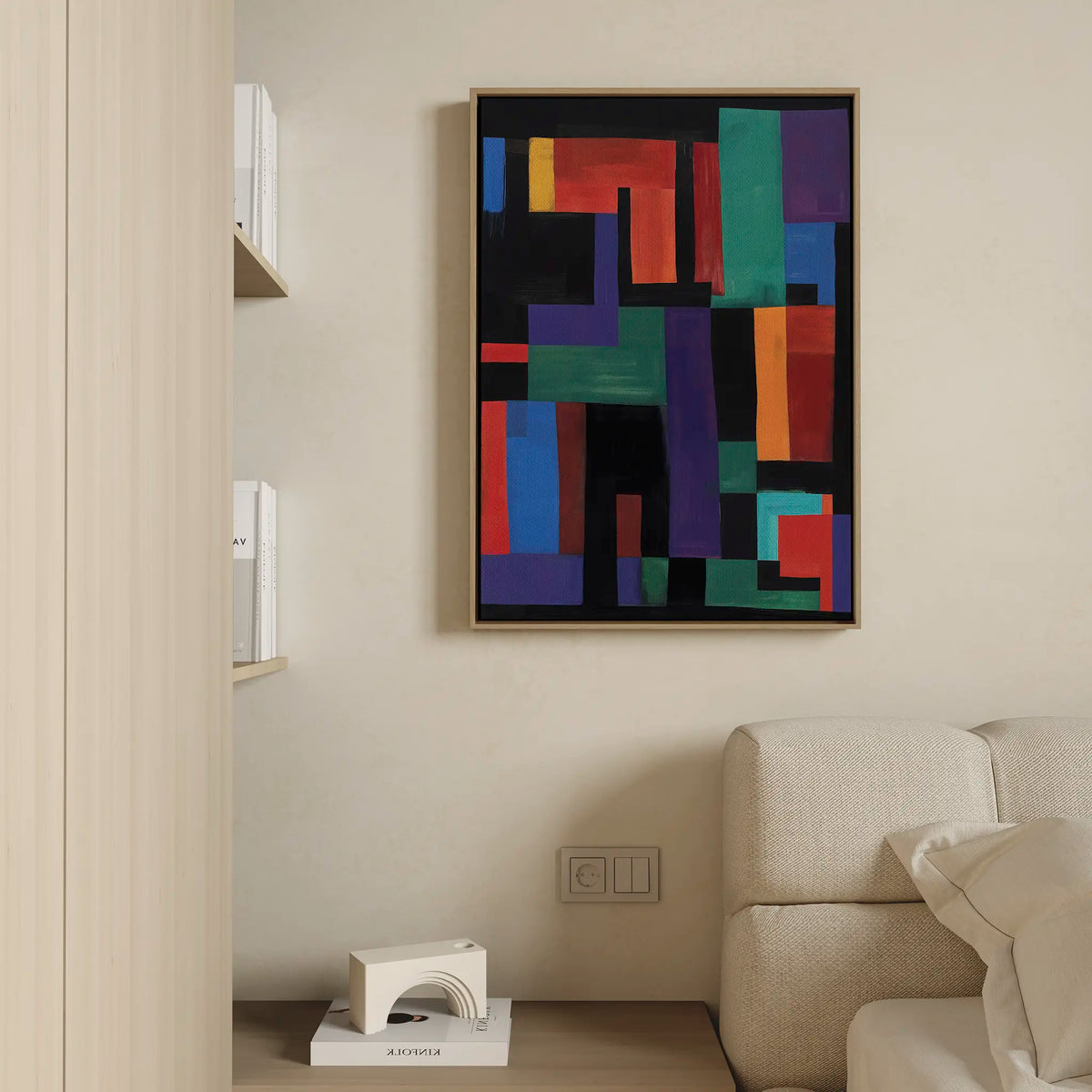 The Geometric Mosaic Canvas Art, featuring a vibrant abstract design, hangs above a light sofa on a beige wall. Nearby, a modern sculpture and books add to the minimalist, cozy style of this contemporary living room.