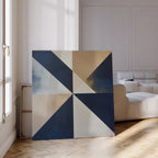 The Geometric Night Canvas Art, featuring blue, beige, and white triangles, leans against a white wall on a wooden floor in a bright modern living room with a white sofa and sunlight streaming in.