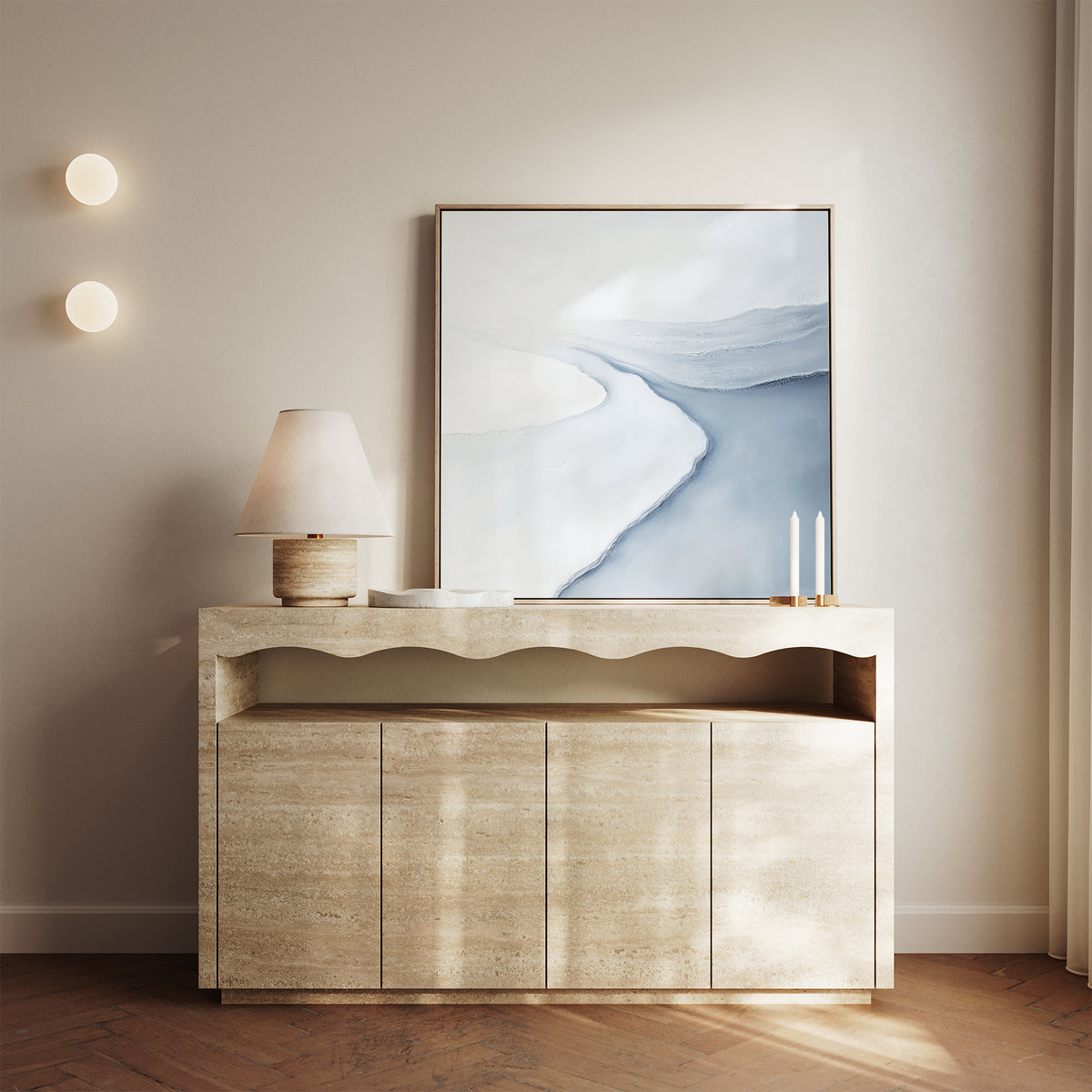A modern console table with a wavy design displays a lamp, two tall candles, and the Glacial Flow Canvas Art in soft blue and white; two round wall lights and sheer curtains finish the modern living room decor.