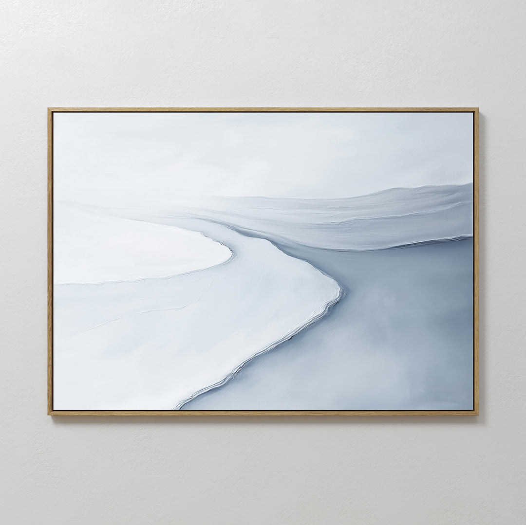 The Glacial Flow Canvas Art – Horizontal features abstract sweeps in white, light gray, and blue, evoking a tranquil river under clouds—perfect minimalist decor for a modern living room with a plain light-colored wall.
