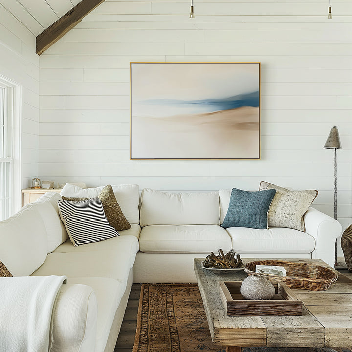 A bright, cozy living room features a white sectional sofa, assorted throw pillows, a rustic wooden coffee table with décor, and the Golden Drift Canvas Art – Horizontal as the focal point against a white shiplap wall.