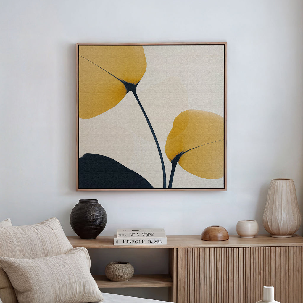 A minimalist living room with neutral-toned furniture features the Golden Leaves Canvas Art—showcasing yellow and black leaf-like shapes—hanging above a light wood sideboard to elevate your decor.