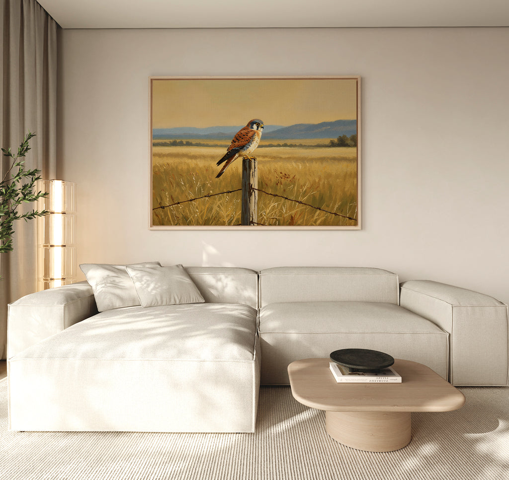 A modern living room featuring a light beige sectional sofa, round wooden coffee table, potted plant, and the Golden Plains Canvas Art showcasing a bird perched on a fence post in a golden field as nature-inspired wall decor.