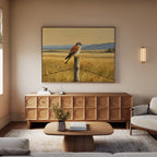 A cozy living room with a light sofa, wooden coffee table, and cabinet. Above the cabinet hangs Golden Plains Canvas Art—a large painting of a bird on a fence in a grassy field with mountains in the background.